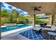 Relaxing covered patio with a ceiling fan, wicker furniture, blue rug, and view of the sparkling pool at 1701 Tesara Vista Pl, Las Vegas, NV 89128