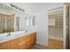 Bright bathroom featuring a dual-sink vanity, large mirror, and a walk-in closet with custom shelving at 1978 Kachina Mountain Dr, Henderson, NV 89012