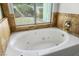 Close-up of a white bathtub with jets and bronze-colored tiling around the window at 1978 Kachina Mountain Dr, Henderson, NV 89012