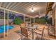 Relaxing covered patio with dining set, seating area, and view of a sparkling pool surrounded by lush landscaping at 2231 Marlboro Dr, Henderson, NV 89014