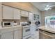 Bright kitchen with white cabinets, tiled countertops, modern appliances, and a view to the backyard patio at 2595 Fort Lauderdale Dr, Las Vegas, NV 89156