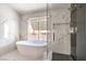 Bright bathroom featuring a modern tub, walk-in shower with gold fixtures and white marble-style tiling from floor to ceiling at 2713 Beachside Ct, Las Vegas, NV 89117