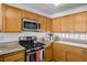 Well-lit kitchen with wooden cabinets, stainless steel microwave and stove, and granite countertops at 3425 Creek River Dr, Las Vegas, NV 89129