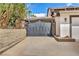 Gated driveway leading to a two-car garage, surrounded by mature trees and greenery at 3916 Green Leaf Dr, Las Vegas, NV 89120
