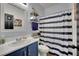 Stylish bathroom with blue vanity, shower with striped curtain, and decorative wall art at 4330 Oasis Hill Ave, North Las Vegas, NV 89085