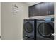 Convenient laundry room equipped with modern, front-load washer and dryer units plus dark wood cabinetry at 63 Harrison Rose Ct, Las Vegas, NV 89110
