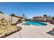 Gorgeous backyard pool with adjacent jacuzzi nestled among palm trees and mature rock landscaping at 6328 Yankee Meadow Cir, Las Vegas, NV 89130