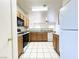 Bright kitchen with white tile flooring, wood cabinets, and granite countertops at 6459 Rusticated Stone Ave # 103, Henderson, NV 89011