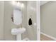 Contemporary powder room with pedestal sink, neutral tones, and decorative mirror at 7128 Port Stephens St, North Las Vegas, NV 89084