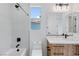Modern bathroom with tub and shower, white tile, and wood grain vanity at 8721 Robinson Ridge Dr, Las Vegas, NV 89117