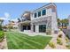 Back of a two-story house shows a green lawn, landscaping, outdoor kitchen and stone accents at 8721 Robinson Ridge Dr, Las Vegas, NV 89117