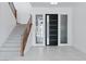 Bright foyer with a modern front door, staircase with wood handrail, and tile flooring at 8721 Robinson Ridge Dr, Las Vegas, NV 89117
