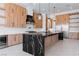 Modern kitchen with black marble island, wood cabinets, stainless steel appliances at 8721 Robinson Ridge Dr, Las Vegas, NV 89117