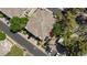 Aerial view of the roofs of tan townhomes, green trees, small community space, a red umbrella, and parked cars at 915 Graceful Moon Ave, Henderson, NV 89015