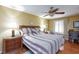 Comfortable bedroom boasts wood floors, a ceiling fan, a bed with decorative pillows, and a work desk at 915 Graceful Moon Ave, Henderson, NV 89015