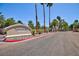 Entrance to Newport Townhomes with paved brick road, a sign, beautiful palm trees, green shrubs and flowers at 915 Graceful Moon Ave, Henderson, NV 89015