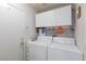 Bright laundry room includes a modern washer and dryer, plus overhead storage cabinets at 915 Graceful Moon Ave, Henderson, NV 89015