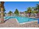 Community pool with clear, blue water, lounge chairs, decorative lights, and palm trees for shading at 915 Graceful Moon Ave, Henderson, NV 89015
