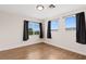 Sunny bedroom with laminate floors, two bright windows and dark curtains at 9630 Tuscola Ct, Las Vegas, NV 89148
