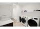 Well-equipped laundry room featuring modern washer, dryer, and built-in sink with ample counter space at 9815 Evergreen Pine St, Las Vegas, NV 89166