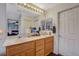 Bathroom with double sinks, a large mirror, wood cabinets, and bright lighting at 1007 Shades End Ave, North Las Vegas, NV 89081