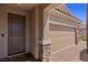 Home's front exterior featuring a stone pillar, front door, and two-car garage at 1047 Atkins Ln, Mesquite, NV 89027