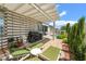 Covered patio features lounge chairs, a grill, and vibrant greenery, perfect for relaxing by the pool at 10579 Garden Rose Dr, Las Vegas, NV 89135