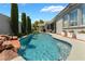 Resort style backyard featuring a sparkling pool with waterfall, lush landscaping, and a covered patio at 10579 Garden Rose Dr, Las Vegas, NV 89135