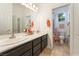 Bright bathroom featuring double sinks with dark wood cabinets, a large mirror, and a shower with a floral curtain at 10579 Garden Rose Dr, Las Vegas, NV 89135