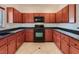 Traditional kitchen showcases wood cabinetry, black appliances, and tile flooring at 1115 Aldenwood Ave, Las Vegas, NV 89123