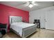 Bedroom showcasing stylish bed, a crimson accent wall and ceiling fan with bright, natural light at 138 Palma Del Rio, Las Vegas, NV 89110