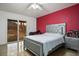 Cozy bedroom features a modern bed frame, a red accent wall and backyard access through sliding glass doors at 138 Palma Del Rio, Las Vegas, NV 89110
