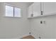 Bright laundry room with white cabinets, matte black hardware, window and wood look floors at 1705 Imperial Cup Dr, Las Vegas, NV 89117