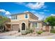 View of a two-story tan home with a two-car garage, arched entryway, and well-maintained front yard landscaping at 2198 Maderno St, Henderson, NV 89044
