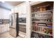 Well-organized walk-in pantry with shelving, stainless steel refrigerator and microwave oven at 2198 Maderno St, Henderson, NV 89044