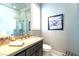 This half bathroom has a stone countertop, dark brown cabinets, a modern sink faucet, and a framed piece of art at 2539 Turtle Head Peak Dr, Las Vegas, NV 89135