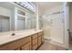 Bathroom featuring double sinks, a large mirror with vanity lighting, and a glass-enclosed shower at 2601 Deer Lake St, Las Vegas, NV 89134