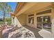 A covered outdoor patio with a view of the landscaped yard, featuring tan stucco and sliding glass doors at 2601 Deer Lake St, Las Vegas, NV 89134