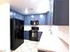 Modern kitchen featuring navy blue cabinetry, black appliances, and white countertops at 3311 Fico Ave, Las Vegas, NV 89141