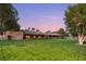 View of the back of a home highlighting an expansive green lawn surrounded by mature trees at 3455 Five Pennies Ln, Las Vegas, NV 89120