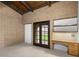 Bedroom featuring exposed beam ceiling, brick walls, built-in desk, and French doors to backyard at 3455 Five Pennies Ln, Las Vegas, NV 89120