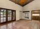 A spacious living room featuring brick walls, beamed ceiling, and double doors to outside at 3455 Five Pennies Ln, Las Vegas, NV 89120
