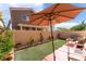 Inviting backyard with artificial grass, large umbrella, patio area, and well-maintained landscaping at 4515 Sandstone Vista Ct, North Las Vegas, NV 89031