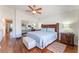 Well-lit main bedroom with wooden bed frame, ceiling fan, a sitting bench and wood floors at 4515 Sandstone Vista Ct, North Las Vegas, NV 89031