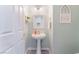 Cozy powder room featuring a pedestal sink, a white door, and a decorative mirror and art at 4515 Sandstone Vista Ct, North Las Vegas, NV 89031