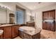 Elegant bathroom with dual vanities, a soaking tub with a granite surround, and a block glass window at 4980 Pensier St, Las Vegas, NV 89135