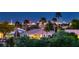 Exterior shot of the home and its community, highlighting lush landscaping, palm trees and a view of the Las Vegas skyline at 4980 Pensier St, Las Vegas, NV 89135