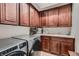 Well-lit laundry room featuring stainless steel washer/dryer, wooden cabinets, and a countertop with a sink at 4980 Pensier St, Las Vegas, NV 89135