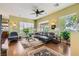Spacious living room with hardwood floors, large windows, stylish furniture, and a ceiling fan at 4980 Pensier St, Las Vegas, NV 89135