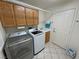 Functional laundry area with washer, dryer, utility sink, and wooden cabinets at 6460 Wagon Wheel Ct, Pahrump, NV 89061